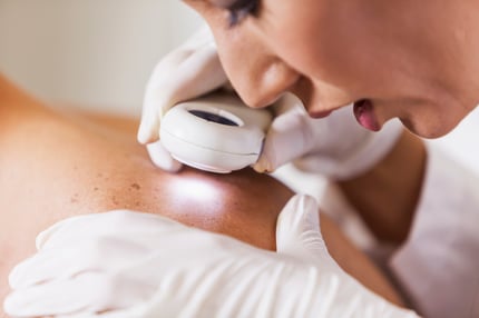 A dermatologist closely examines a patient’s skin