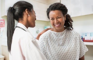 A doctor speaks with her patient, who is wearing a hospital gown
